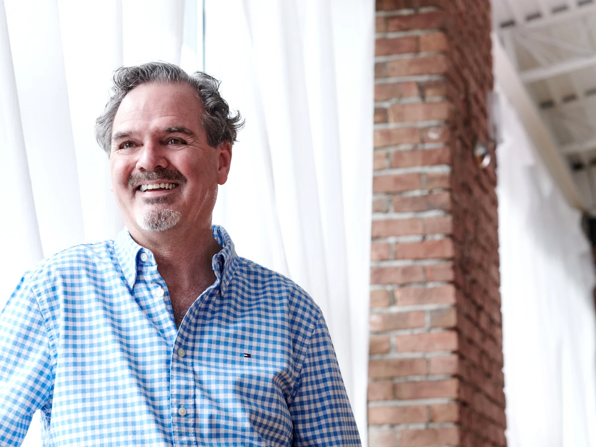 Daniel Roth beside a curtain and brick wall
